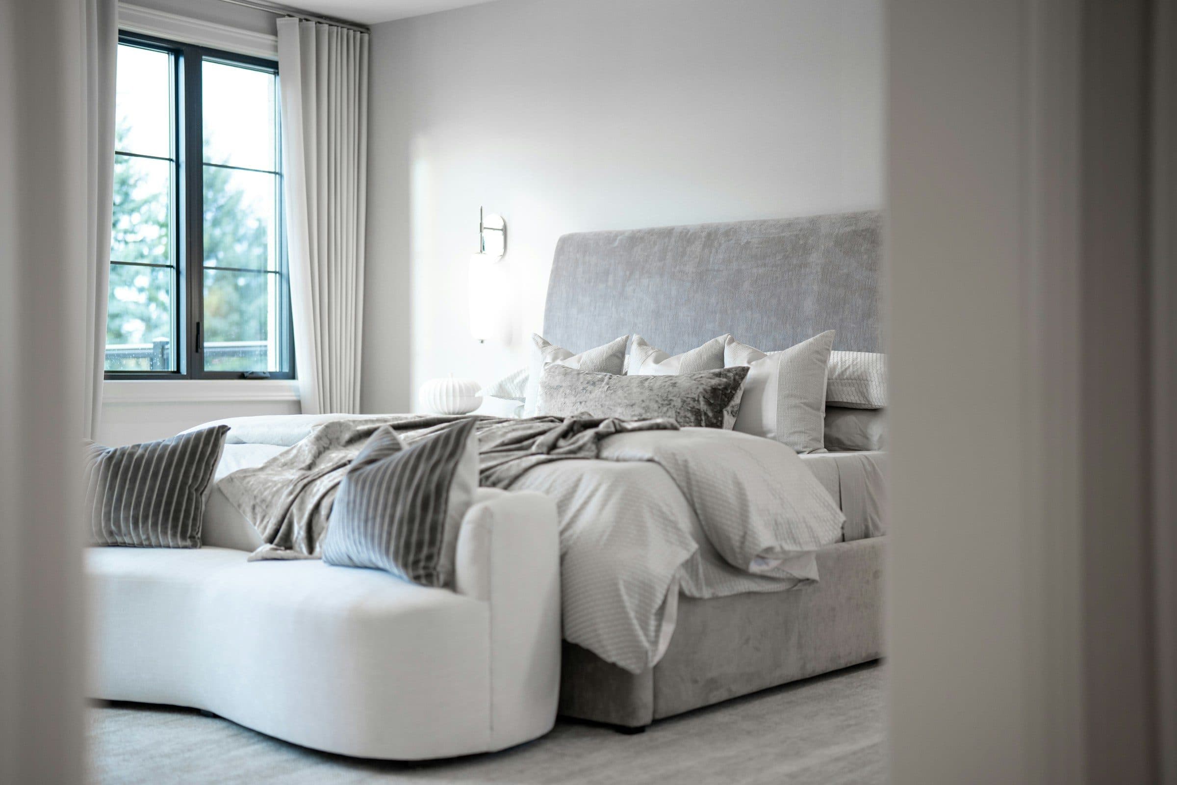 Quarto sereno com roupa de cama branca e luz natural.
