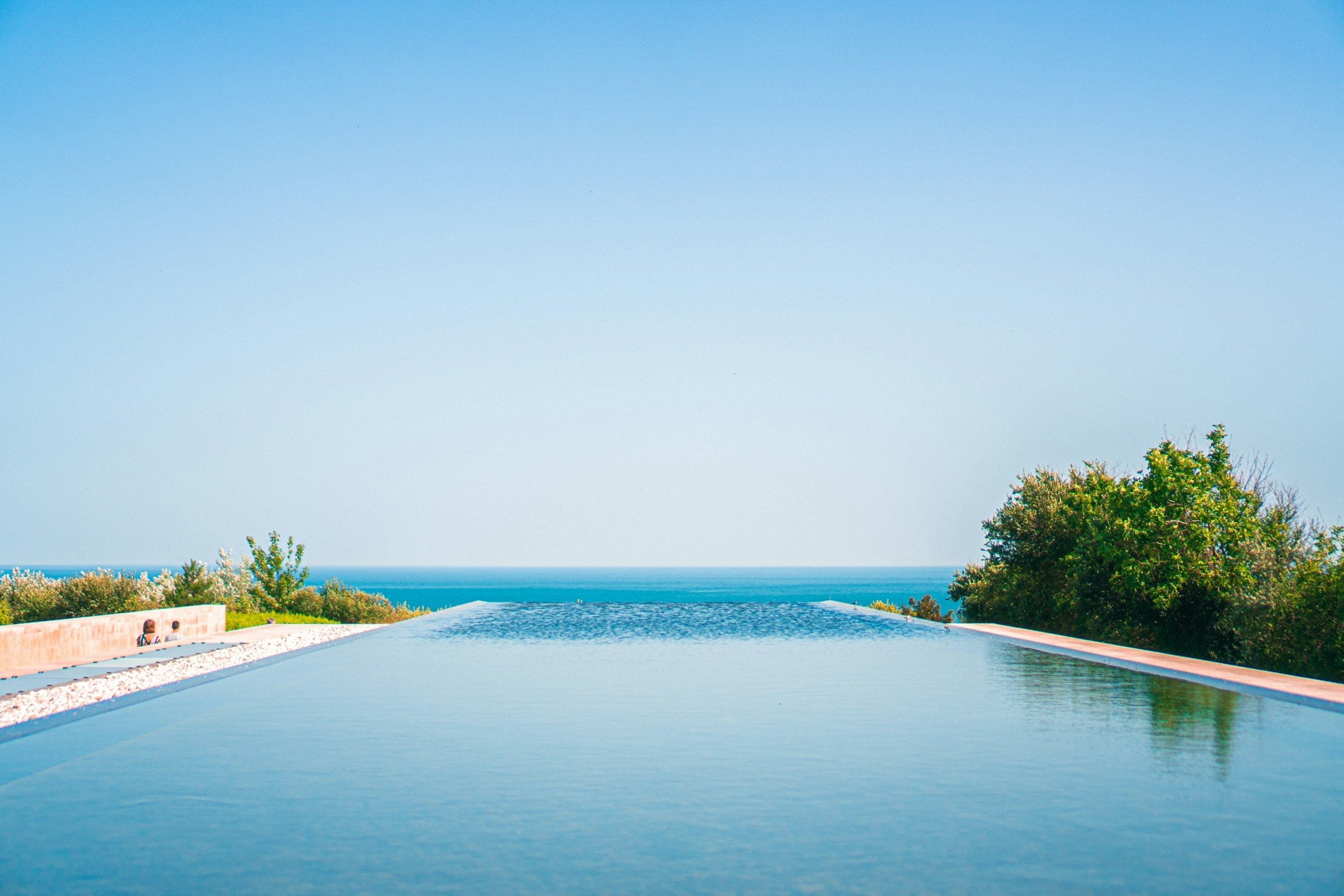 Piscina infinita que se funde com o mar sob um céu limpo.